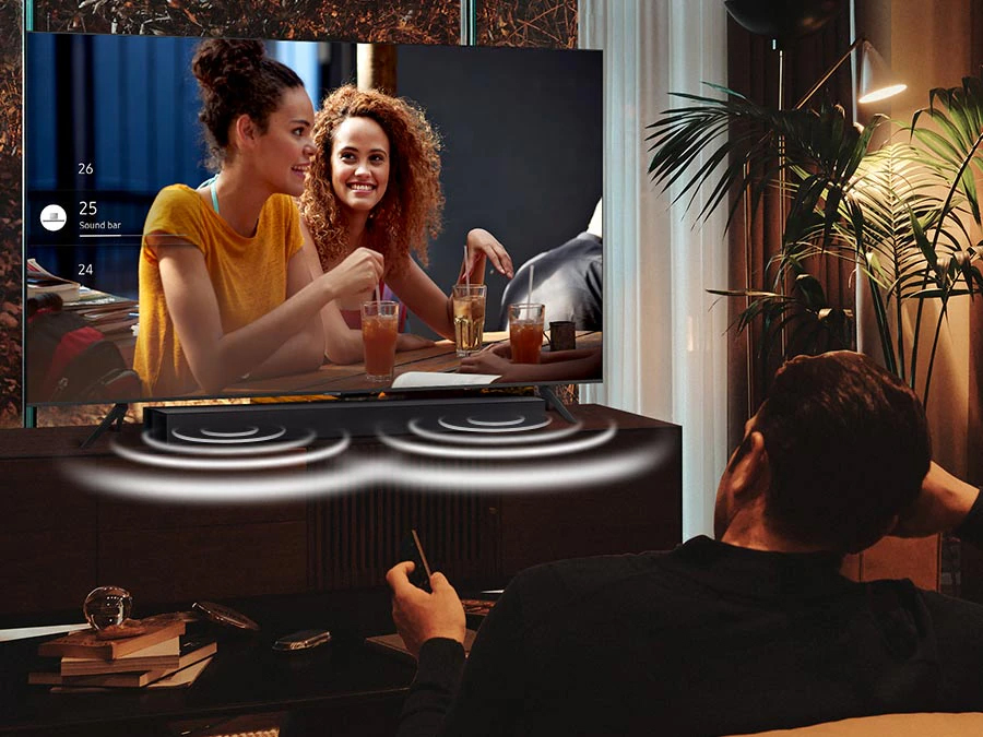 Ένας άντρας βλέπει τηλεόραση τη νύχτα με το Soundbar ρυθμισμένο στη Νυχτερινή λειτουργία. Ο ήχος από τα πλαϊνά ηχεία του Soundbar τονίζεται κατά τη διάρκεια της νύχτας.